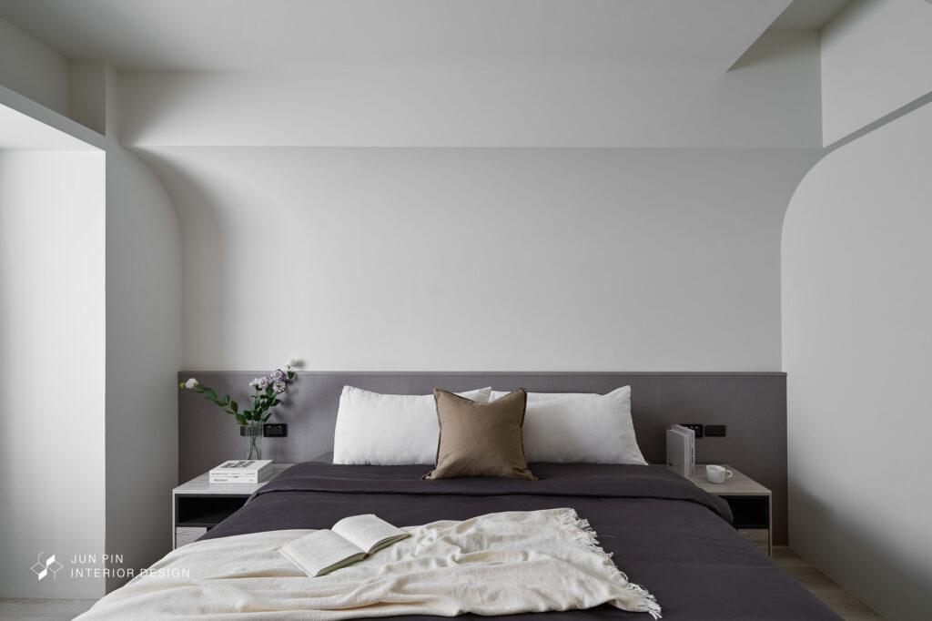 臥室整體以白色及淺色木頭為主， 讓臥室散發溫暖柔和的質感， 透過弧形的設計修飾床頭壓樑的結構。