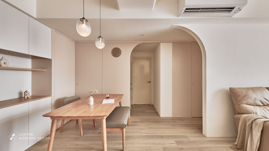 餐廳空間延續溫暖的木質調性，搭配極具設計感的奶茶色餐邊櫃，採用曲面設計，減少銳利感，讓動線流暢舒適。吊燈選用兩盞簡約玻璃燈泡，低調中帶有精緻感，微微透出的光線，像是一勺暖暖的奶泡，點綴了整個用餐氛圍。