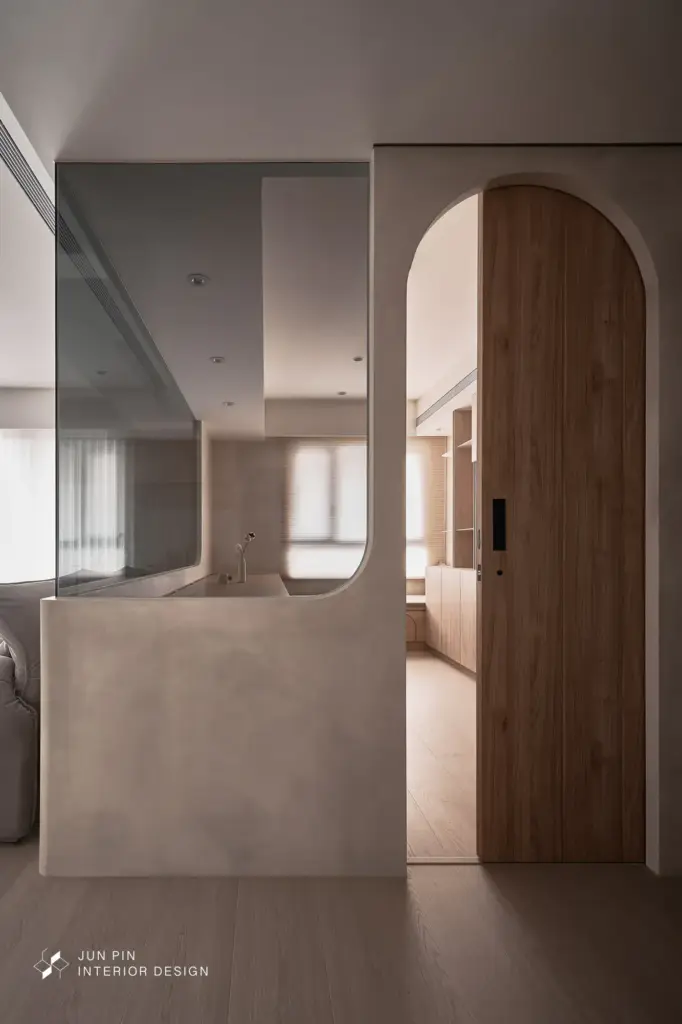 弧形拱門、隱藏門片、藤編門設計，讓動線過渡柔和流暢。特殊漆牆面隨光線變化展現細膩肌理，在極簡中保有溫度與深度。