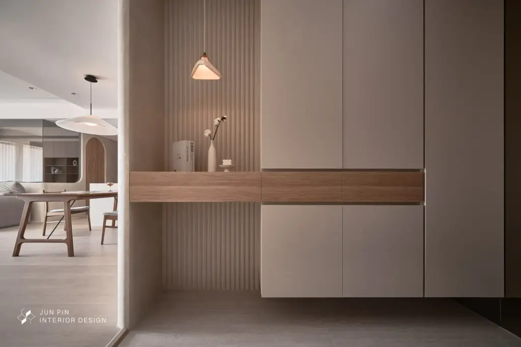 玄關以「放大尺度、弱化界線」為核心概念，配置超大片穿衣鏡延伸視覺深度，電箱則隱藏於櫃體之中，讓立面保持乾淨純粹。