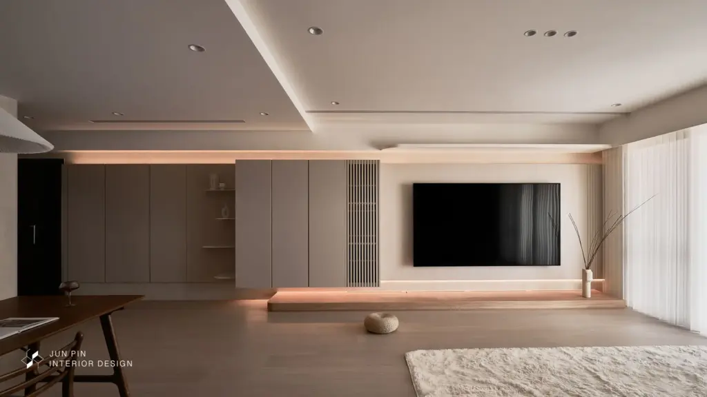 電視牆以溫潤質感材質搭配間接照明，讓牆體量感變得柔和而沉靜。線材與設備全數隱藏，讓視覺回歸純粹。