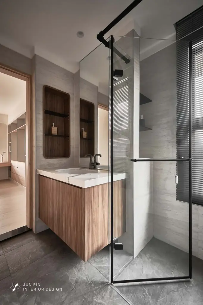 客浴室則以沉穩灰調呈現，搭配木紋地磚與圓鏡背光，結合格柵元素，營造如飯店般的精緻質感。