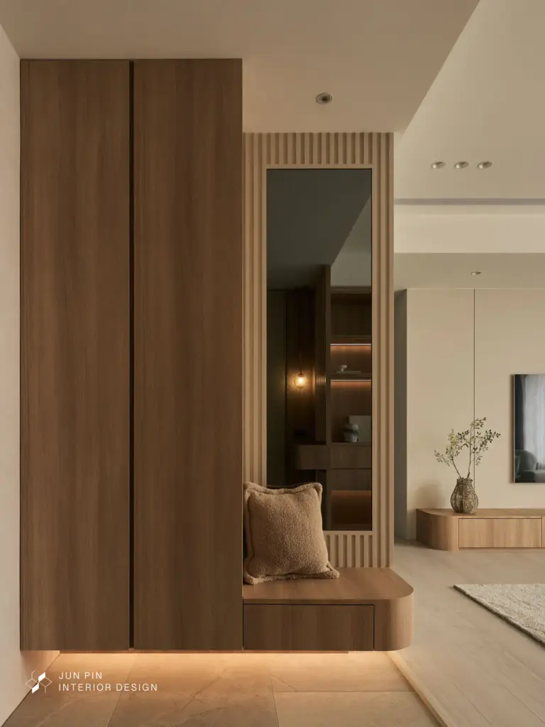 玄關引光術： 入口處設置格柵屏風，確保隱私的同時保持視覺穿透性，搭配懸空穿鞋椅，營造輕盈的進門儀式感。