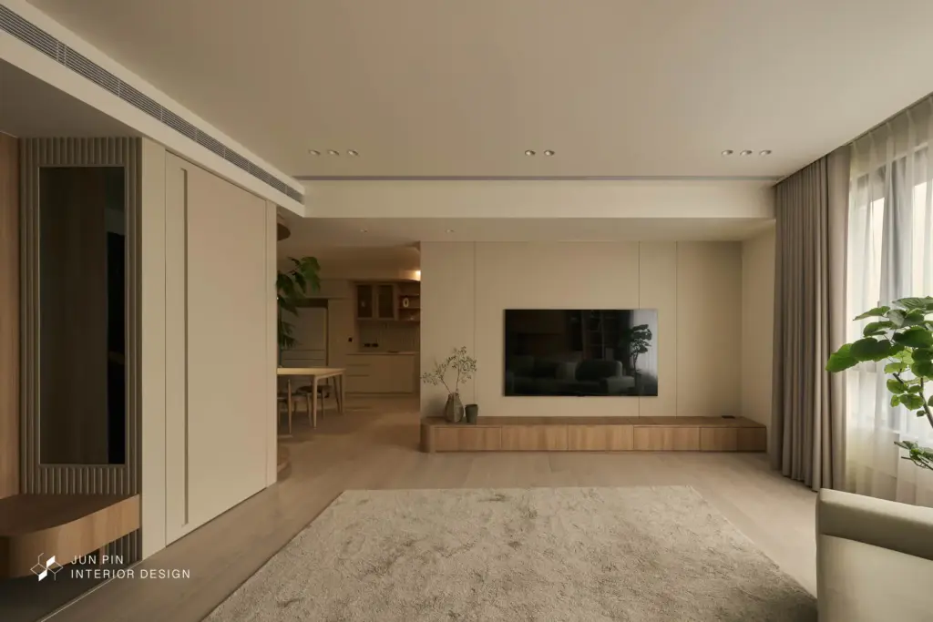 客廳以素面極簡的大尺度電視牆作為主視覺，沙發背牆則運用大面積木紋材質，延續整體溫潤基調。