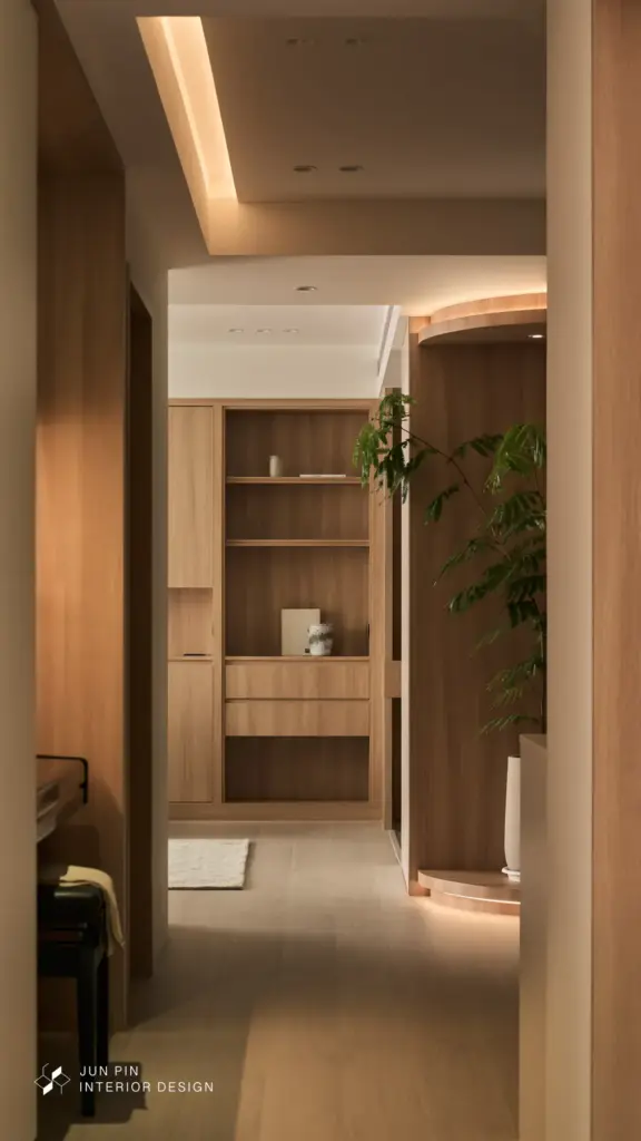 客廳配置素面電視牆與大面積木質沙發背牆，將儲藏空間隱藏於門片之後，維持乾淨俐落的空間輪廓。