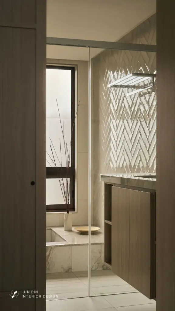 主浴的療癒儀式： 主浴提升至精品飯店規格，壁面運用優雅的人字拼工法，地坪則以異材質分割乾濕區。降板式浴缸與面盆檯面統一使用大理石鋪設，展現材質的細節變化。