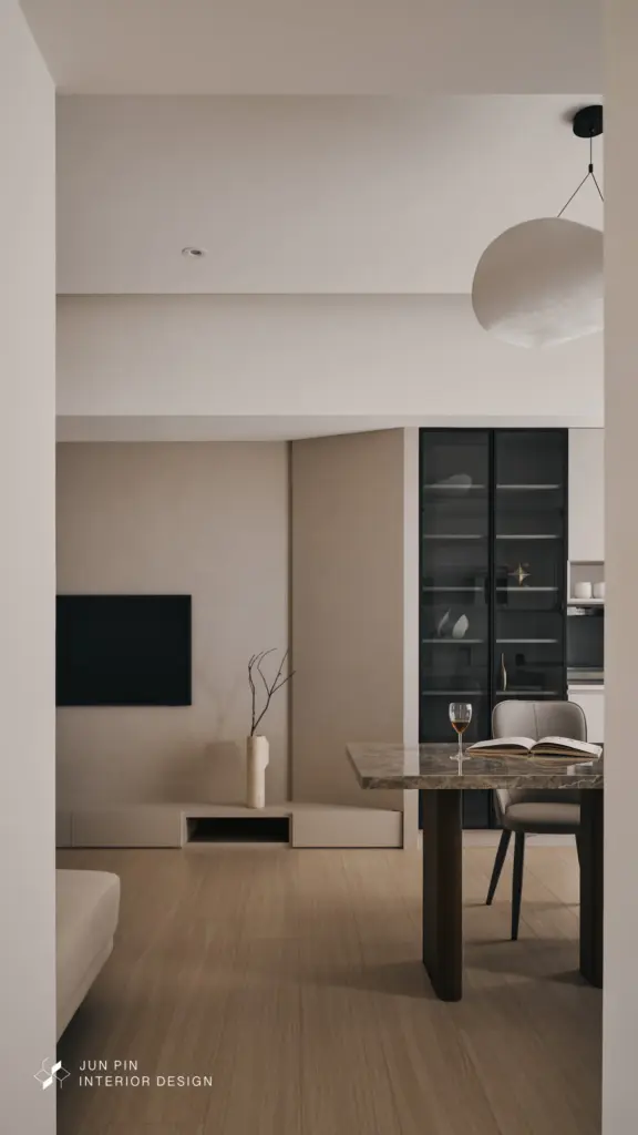 電視牆以霧面特殊塗料鋪陳細膩紋理，搭配退縮量體與弧形延伸設計，弱化原有柱體與轉角的存在感，也讓視線在空間中更加柔順流動。整體不強調繁複裝飾，而是用乾淨的牆面、柔和的材質與恰到好處的留白，創造沉靜、舒服且耐看的客廳氛圍。