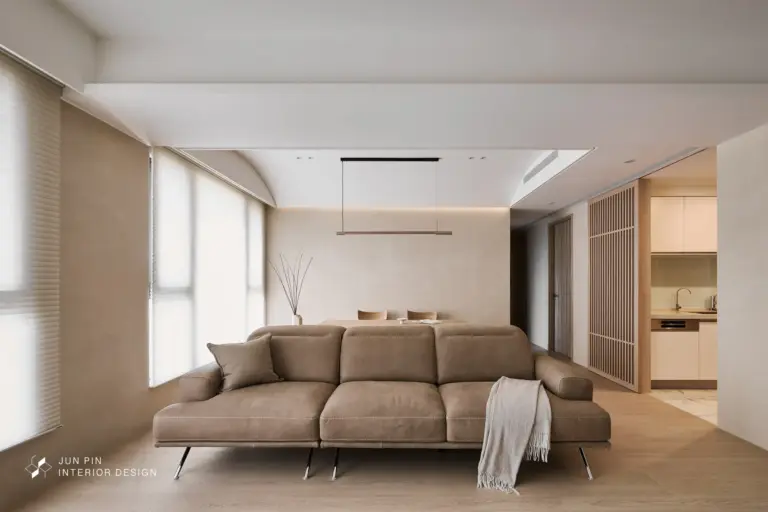 奶茶色沙發與木質地板構成的日式無印風客廳設計，搭配格柵與間接照明呈現溫和空間感