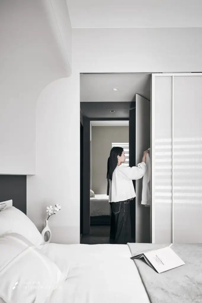 主臥運用灰玻的反射特性放大狹長更衣區體感，並以鋁框長紅玻璃門片阻絕衛浴濕氣，維持睡眠區的純淨度。