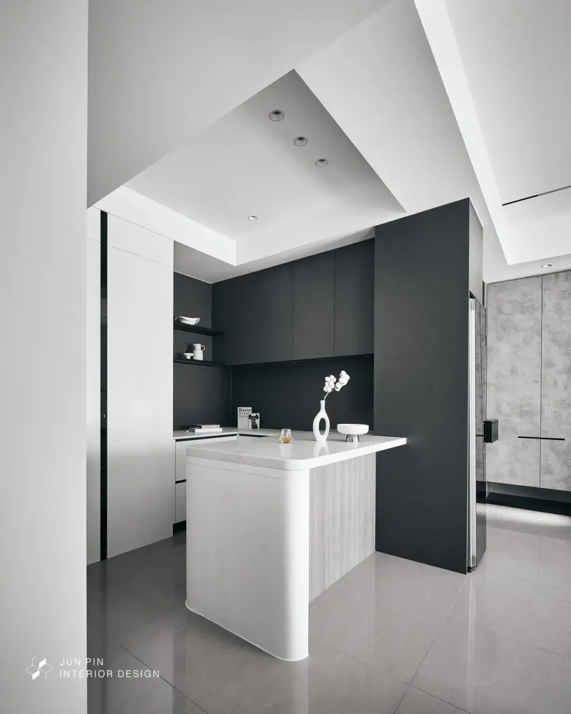 考量屋主一人使用的習慣，捨棄傳統大型餐桌，改從餐邊櫃延伸出一座銀湖石材中島。這座吧檯既是平日用餐區，也是朋友來訪時的社交核心，下方更貼心留空作為掃地機器人的家，兼具美感與實用性。