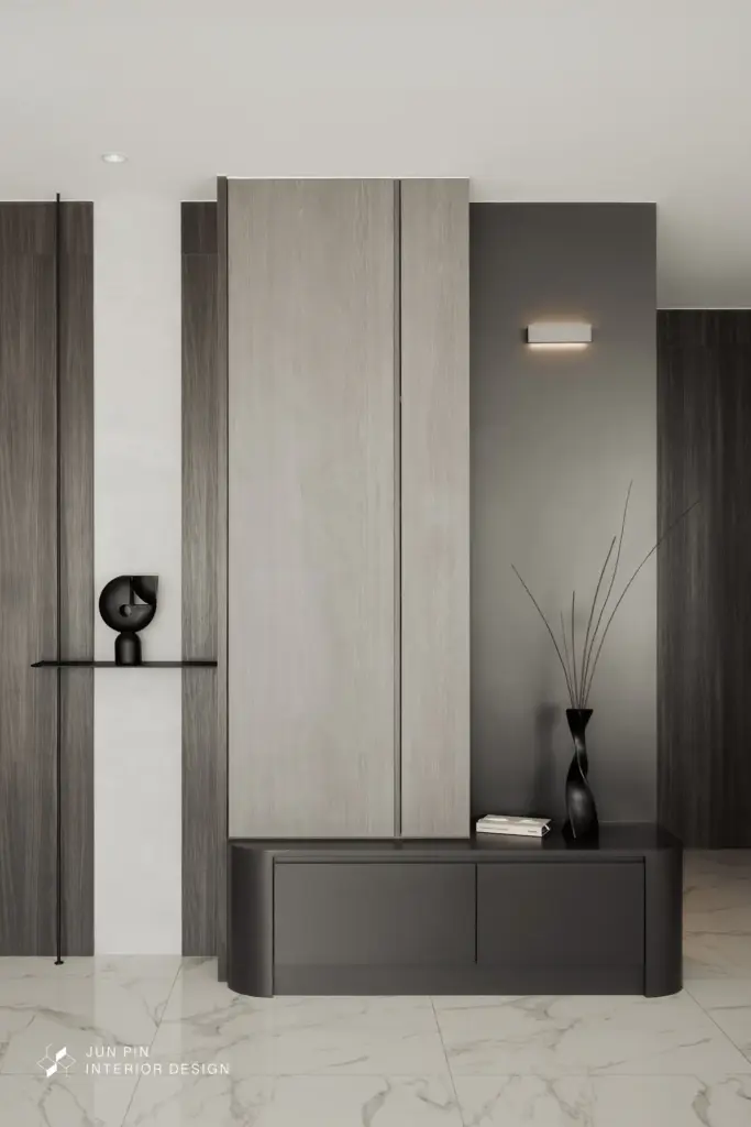 因屋主希望能保留原建商給的石紋地磚，因此設計師在玄關處也沒有特地設置落塵區，進門正對面是玄關櫃體，以黑色的櫃體作為玄關櫃，與白色的石紋地磚產生較明顯的對比，展現明顯的層次感。