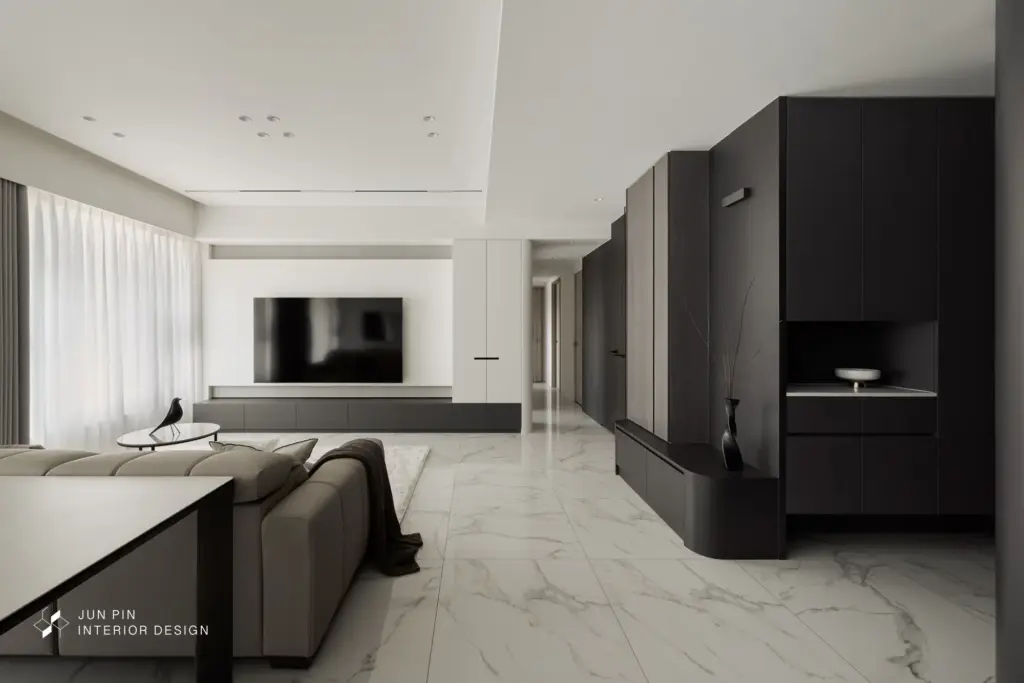 進入客廳，同樣使用建商的石紋地坪，電視牆使用烤漆白色加上特殊漆創造出低調的層次感，而電視牆和電視邊櫃皆使用白色烤漆，讓空間留白，也藉此展現空間乾淨、簡單的視覺效果。