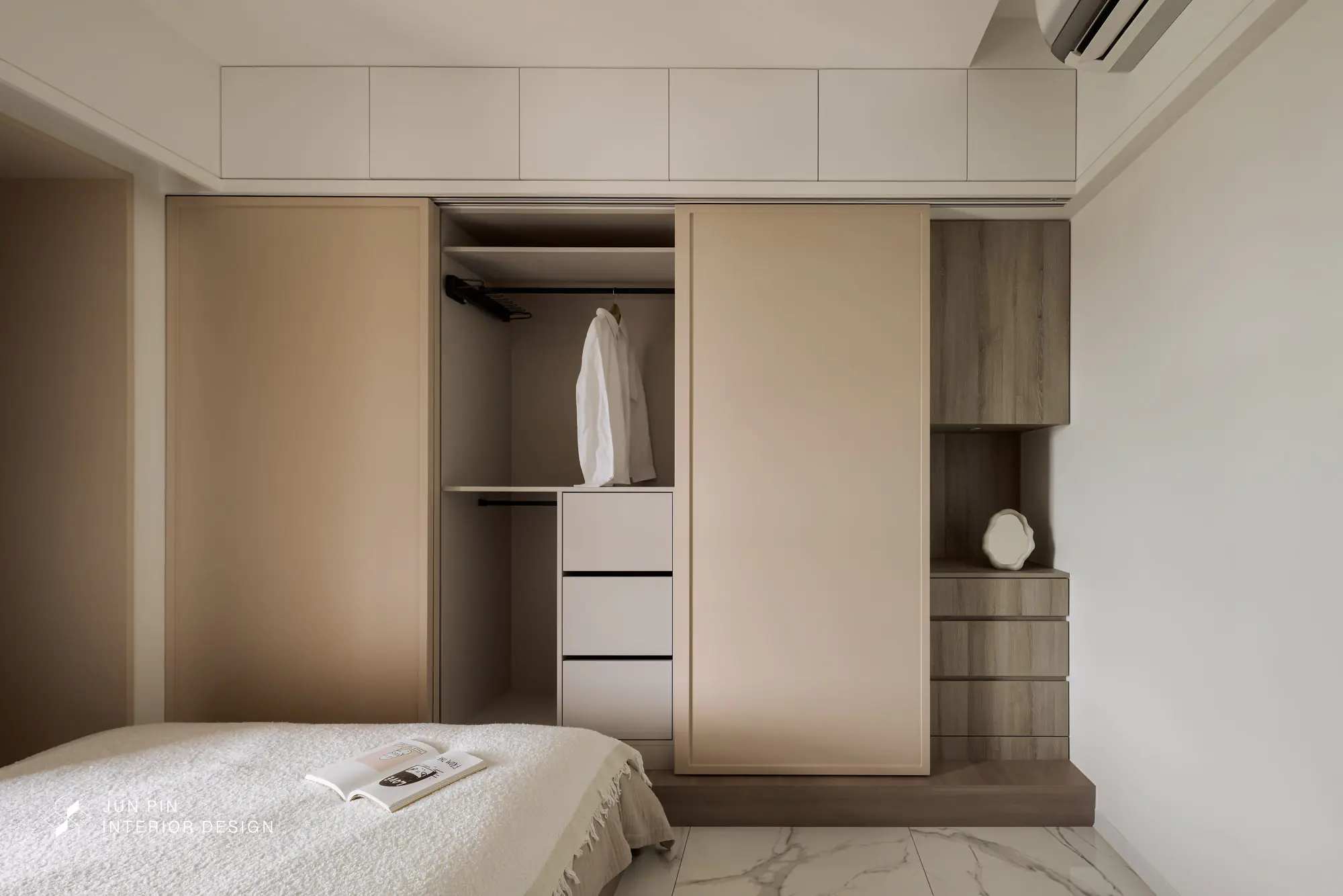 床尾架高地板並設置滑門衣櫃，節省開門所需的空間，右側還以不同木色做了小邊櫃，當滑門衣櫃全拉起時，還能保留空間的層次感。