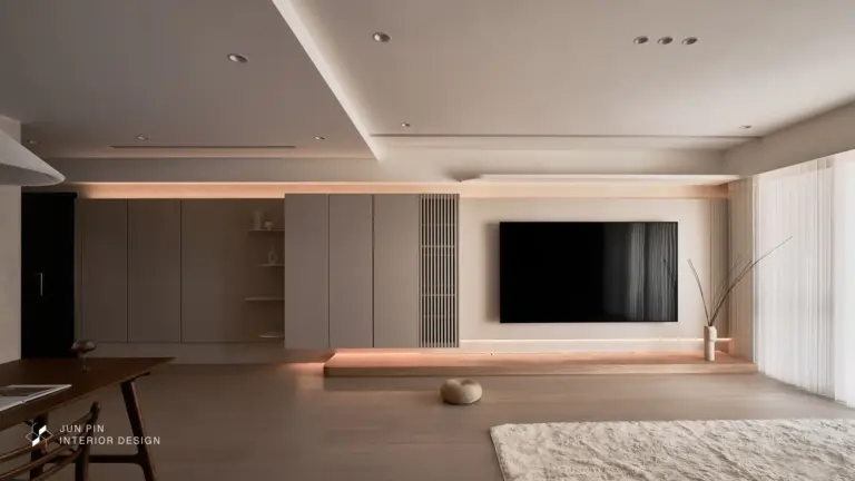 米色牆面與淺色櫃體結合的無印感極簡空間，搭配織品與暖色燈光，提升生活溫度。