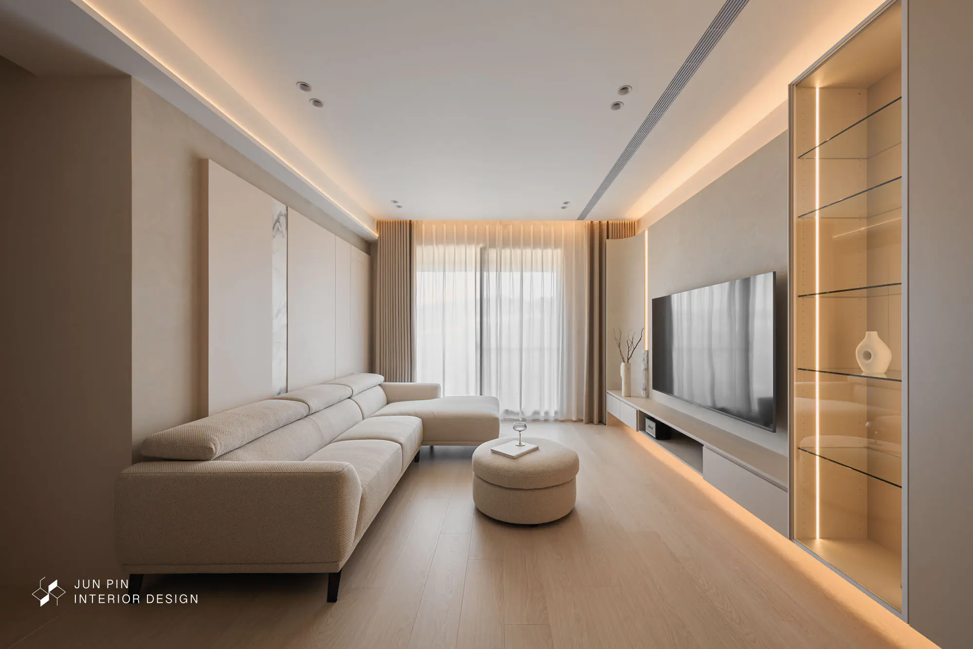 一走進屋內，就被大面積鋪陳的奶茶色與手刷特殊漆（藝術漆）牆面給溫柔擁抱。天花板採用大面積的圓弧導角設計，視覺感一路從玄關延伸至落地窗，不僅巧妙修飾了吊隱式冷氣，更整體看上去空間更為放大。窗簾盒挑高設計，再度放大客廳視覺。