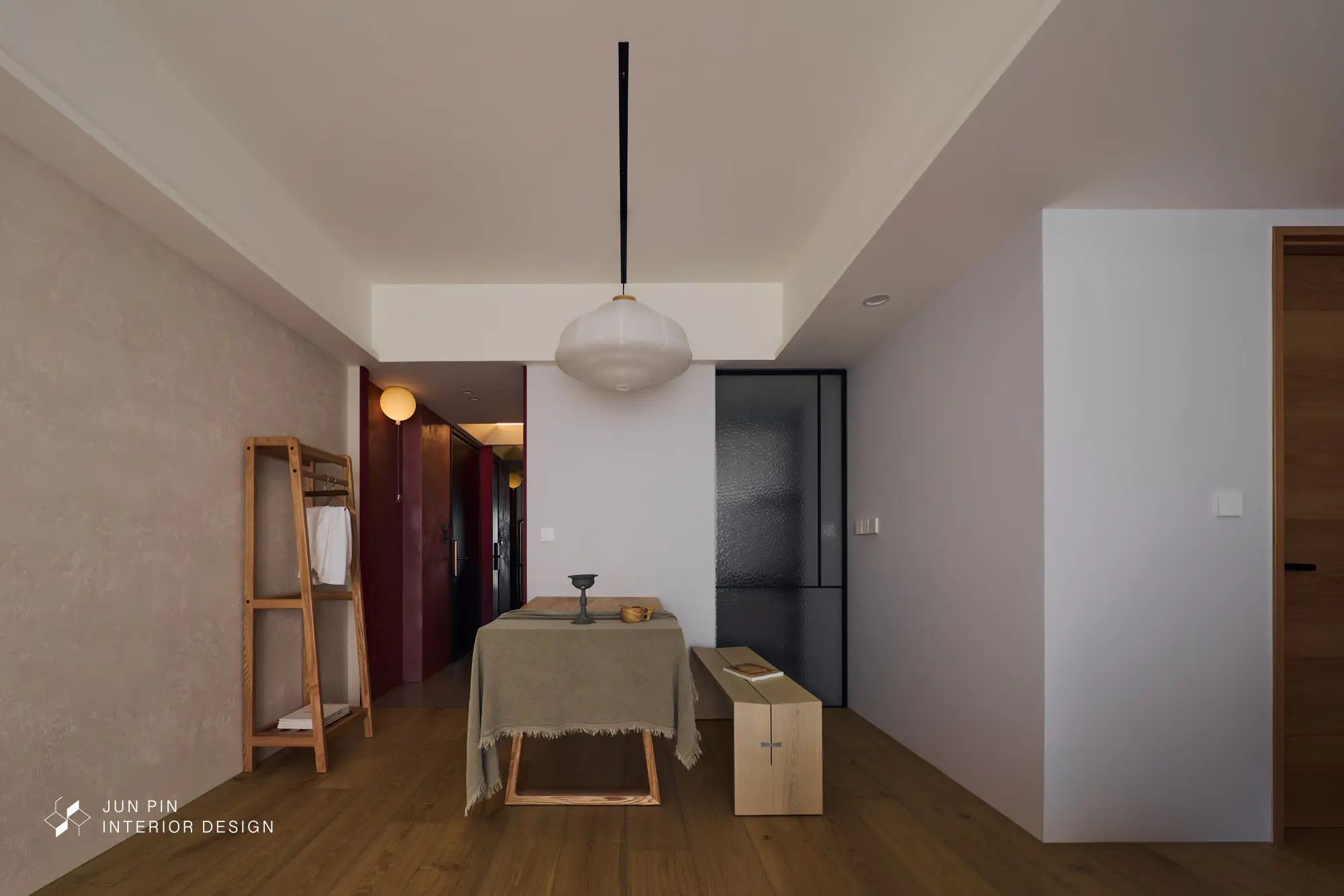 郡品室內設計－林口立軒天翠21坪新成屋餐廳廣角，扁球形紙燈吊燈，原木餐桌長凳組合，左側木梯衣架，背景酒紅色門洞通玄關，右側長虹玻璃拉門連廚房