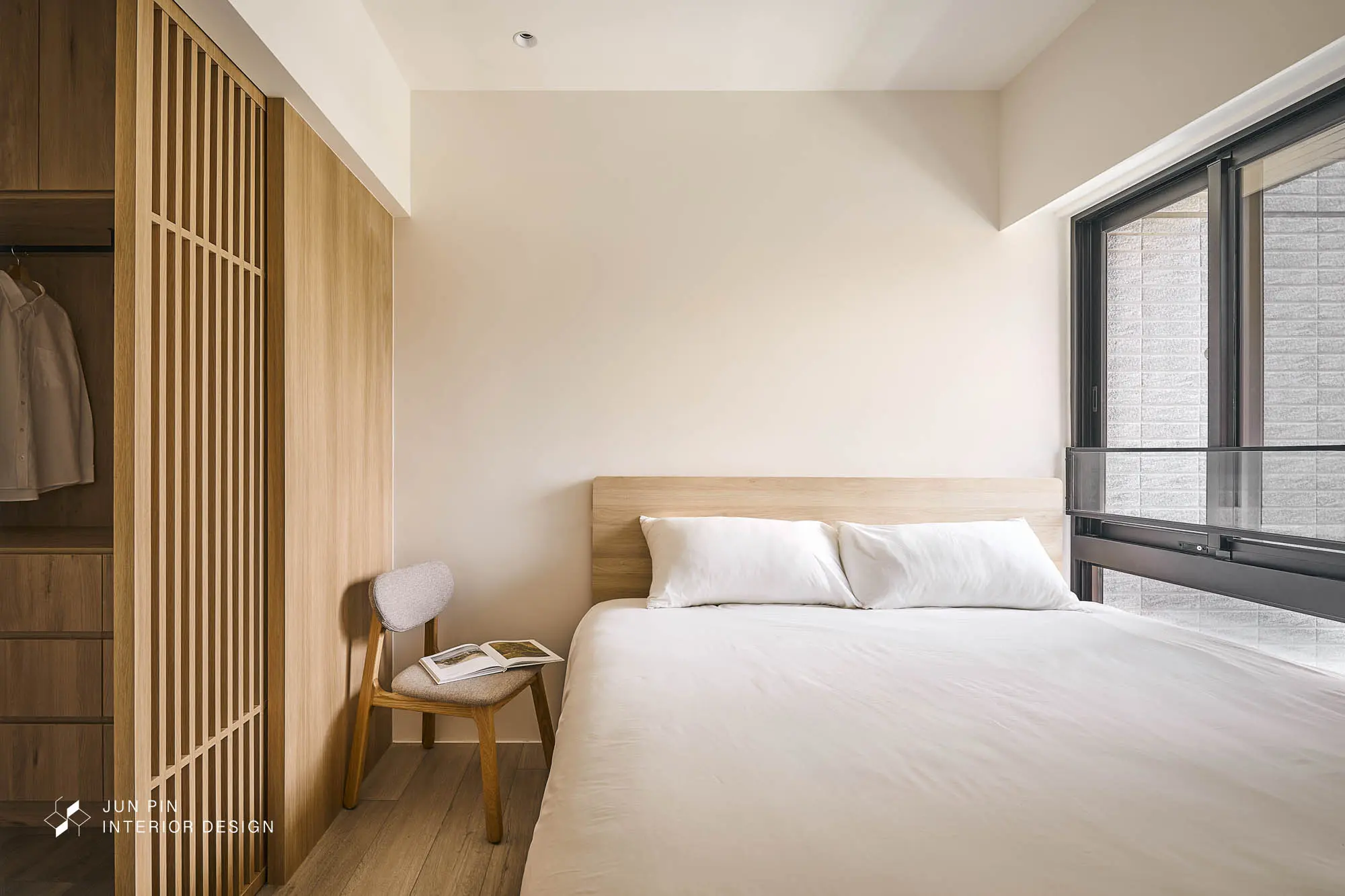 主臥以格柵拉門劃分睡眠區與更衣室，米白牆面搭配淺木紋床頭板，呈現清爽日式極簡風格。