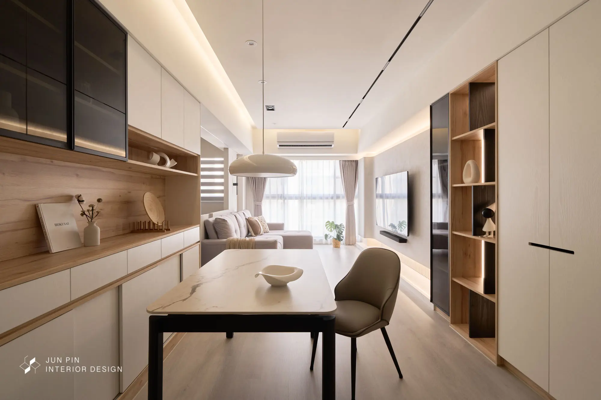一鏡看盡餐廳備餐櫃、餐桌、灰色沙發、電視牆與沙發後方開放式書房；天花軌道燈＋周邊間接光鋪陳整體光環境。