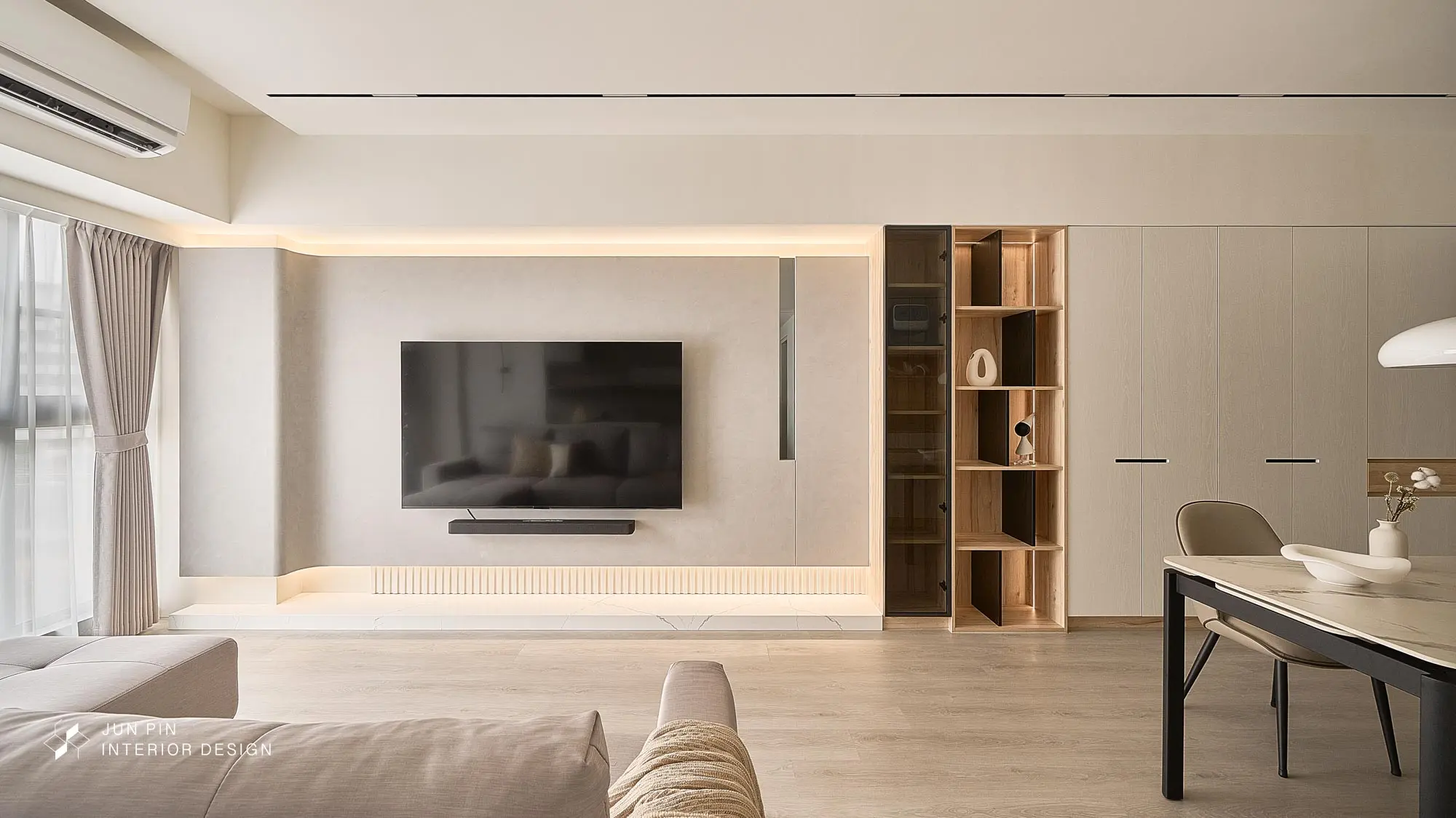 特殊漆主牆搭壁掛電視與 soundbar，下緣直紋燈帶＋藏間接光；右側茶玻＋木質開放展示櫃，接續整面白色系統櫃。